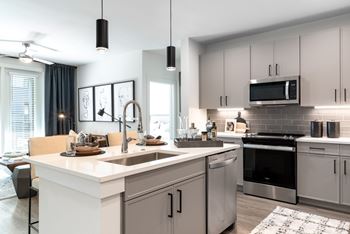 A modern kitchen with a white countertop and stainless steel appliances.